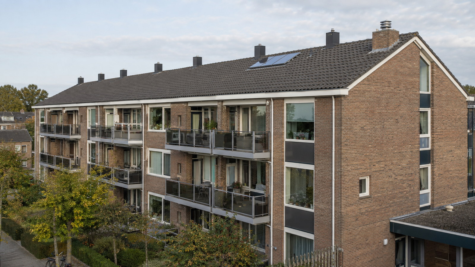 Appartementengebouw van vier woonlagen met balkons, grote raampartijen en een donker pannendak
